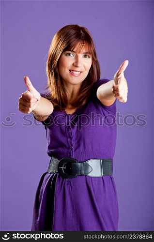 Beautiful and happy young woman with thumbs up, over a violete background