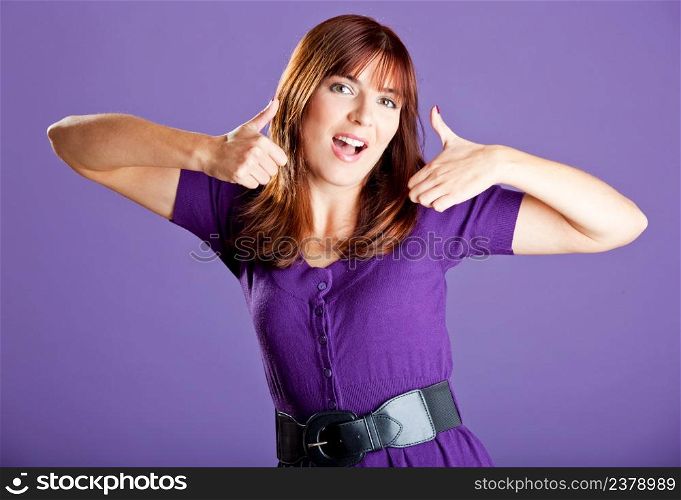 Beautiful and happy young woman with thumbs up, over a violete background
