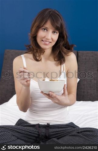 Beautiful and healthy young woman eating a cup of cereals with yogurt