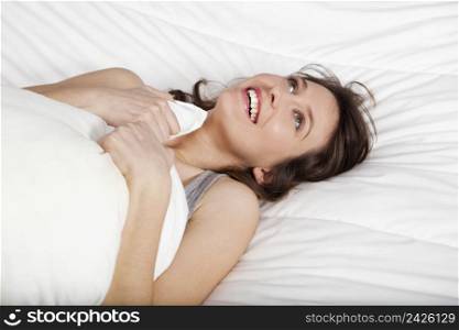 Beautiful and natural young girl on the bed laughing