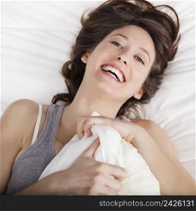 Beautiful and natural young girl on the bed laughing 