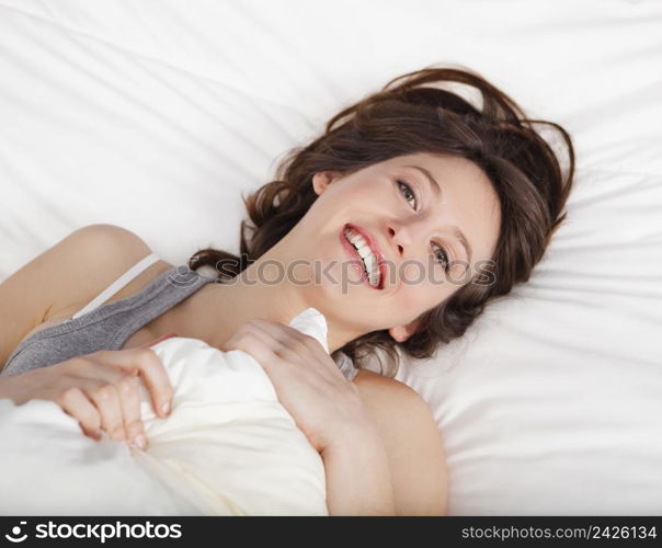 Beautiful and natural young girl on the bed laughing