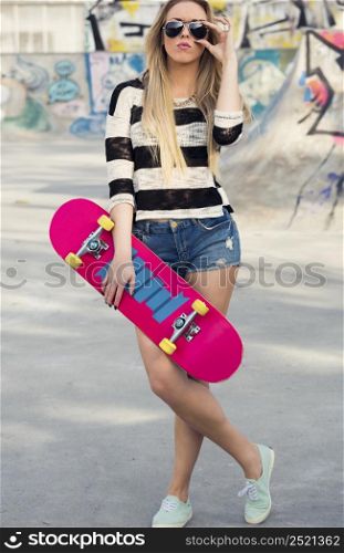 Beautiful and sexy street girl posing with her skateboard