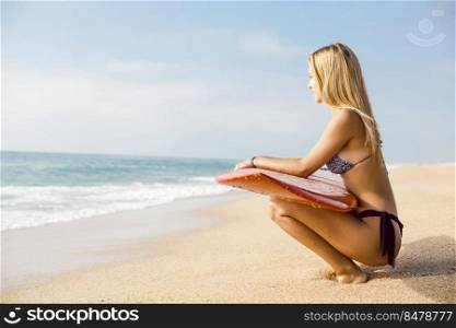 Beautiful and sexy surfer girl holding a surfboard and checking the waves