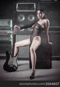 Beautiful and sexy woman in lingerie sitting in a recording studio holding a electric guitar.