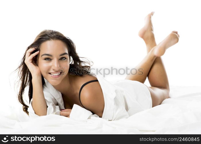 Beautiful and sexy woman lying on bed and smiling, isolated on white background