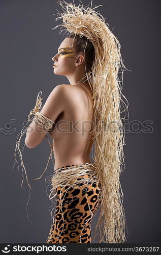 beautiful and sexy woman with raffia hair and a ethnic costume in a shot over dark with creative make up