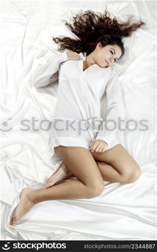 Beautiful and sexy young woman lying on a bed