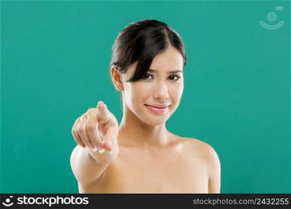 Beautiful and young asian woman pointing with her right hand, over a blue background