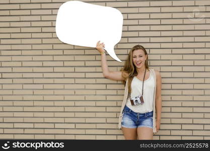 Beautiful and young teenager holding a thought balloon, in front of a brick wall