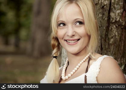 Beautiful anf happy girl sitting close to a tree and enjoying the day