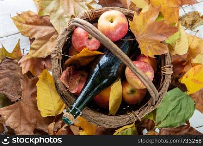 beautiful apples and a bottle of cider, on autumn leaves