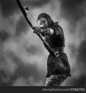Beautiful archery woman aiming, sky on background, black and white image