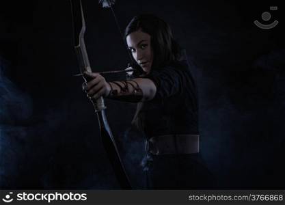 Beautiful archery woman aiming, smoky background