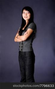 Beautiful Asian American business career woman standing in grey casual clothes with arms crossed, isolated.