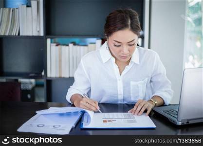 beautiful Asian business women checking document and using notebook and smiling happy for working