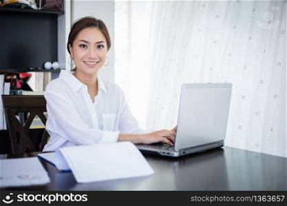 beautiful Asian business women checking document and using notebook and smiling happy for working
