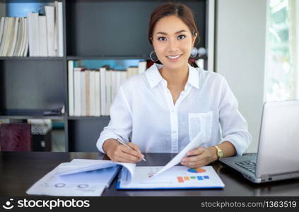 Beautiful Asian business women checking document and using notebook working from home for social distance and self responsibility concept