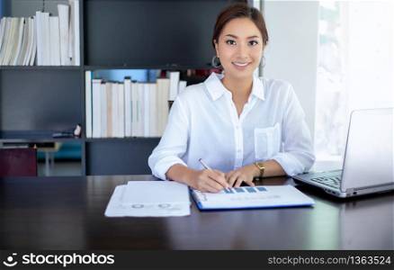 Beautiful Asian business women checking document and using notebook working from home for social distance and self responsibility concept