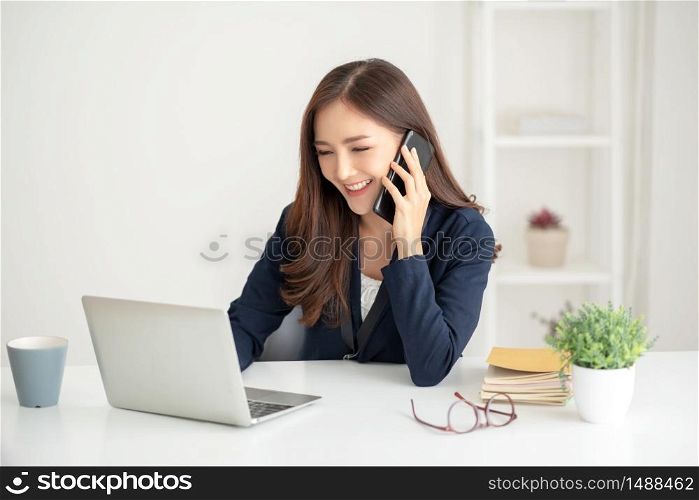 Beautiful Asian businesswoman talking with customer by cell phone at the office.