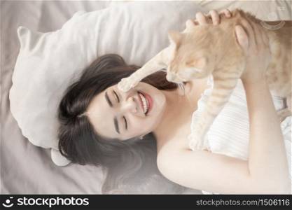 Beautiful asian cat lover woman is playing with cat in her room