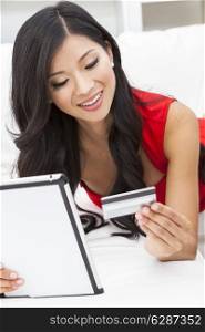 Beautiful Asian Chinese woman using a credit card for on line shopping on the internet with a tablet computer