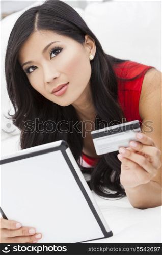 Beautiful Asian Chinese woman using a credit card to shop on the internet with a tablet computer