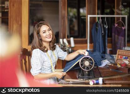 Beautiful asian dressmaker in workroom .designer woman keeping arms crossed and looking at camera with smile while standing in workshop. Beautiful asian dressmaker in workroom