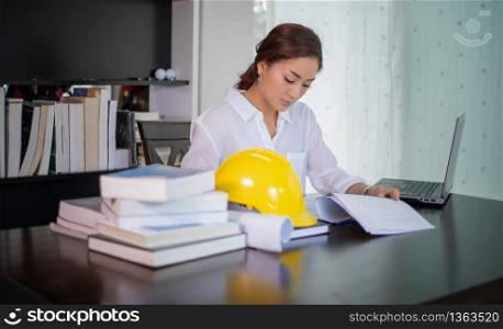 Beautiful Asian engineering women checking document and using notebook working from home for social distance and self responsibility concept