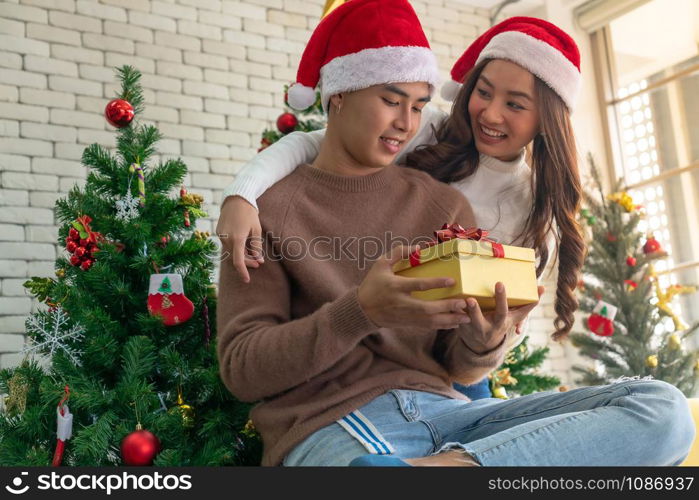 beautiful asian girl give surprise christmas gift to her boyfriend in Christmas holiday season greeting.