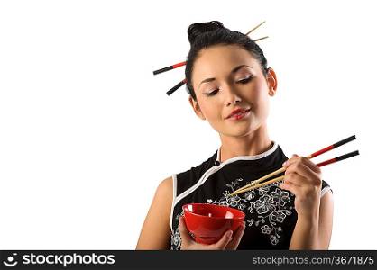 beautiful asian girl in japanes dress eating oriental food from a red cup using chopstick