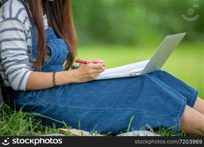 beautiful Asian girl student holding books and smiling at camera and learning and education concept on park in summer for relax time