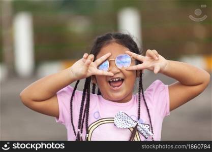 Beautiful Asian kid with long hair wearing glasses smiles happily after her baby teeth fall out.