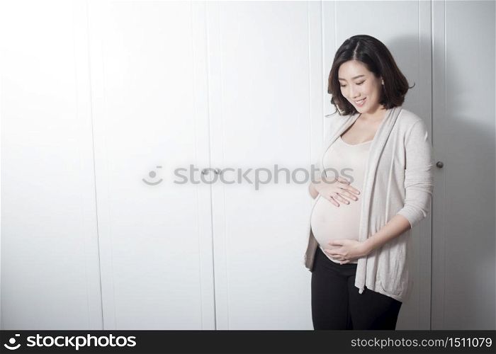 Beautiful asian pregnant woman expecting baby and touching her belly