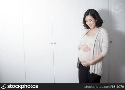 Beautiful asian pregnant woman expecting baby and touching her belly