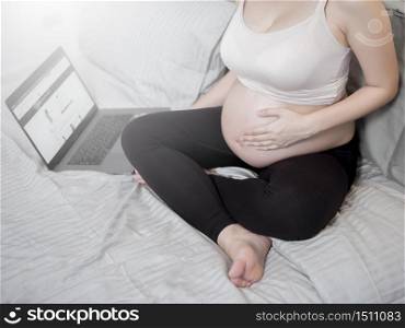 Beautiful asian pregnant woman is working with her laptop