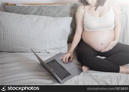Beautiful asian pregnant woman is working with her laptop