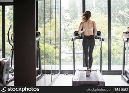 Beautiful asian sport woman is running on treadmill in the gym