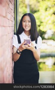 beautiful asian teenager toothy smiling face using smarphone in hand