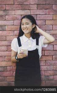 beautiful asian teenager toothy smiling face using smarphone in hand