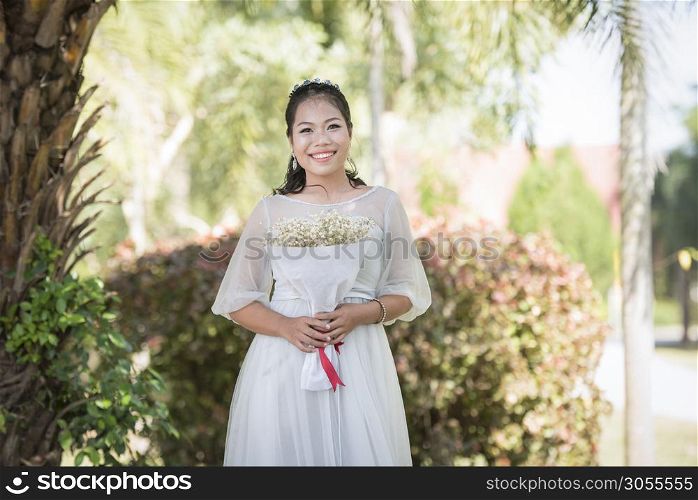 Beautiful asian woman bride portraits smiling and hold flower bouquet in the outdoor garden park