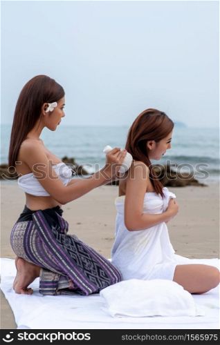 Beautiful asian woman enjoying spa massage therapy on the beach.