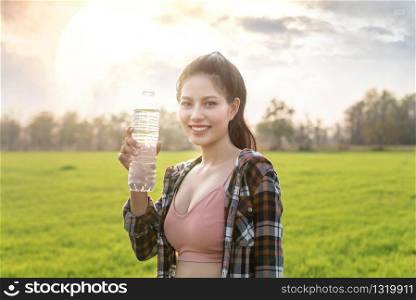 beautiful asian woman holding drinking water after workout. woman holding drinking water