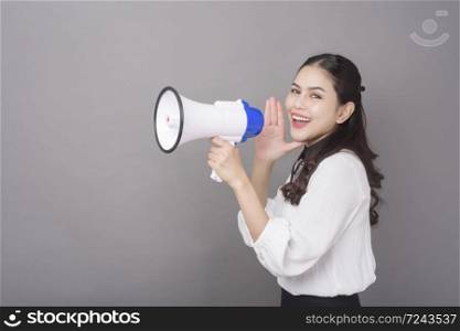 Beautiful asian woman holding megaphone on gray background studio