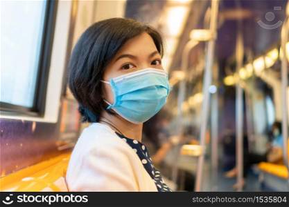 Beautiful Asian Woman in protective face mask for coronavirus or covid-19 or pollution protection inside commuter train travelling to work. Businesswoman in New normal and social distancing life.