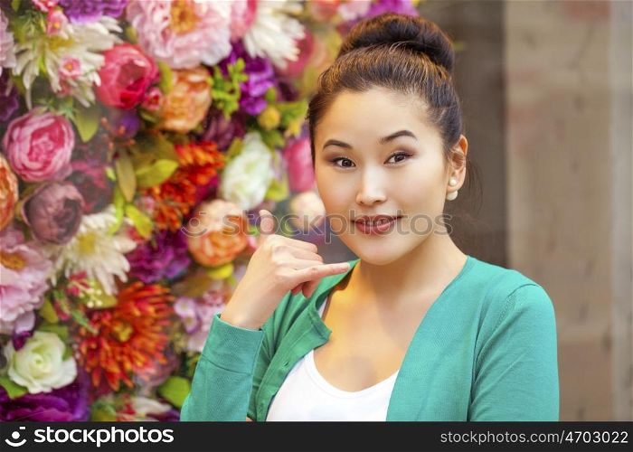 Beautiful asian woman making a call me gesture, indoor