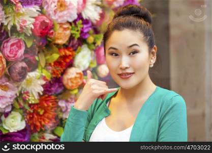 Beautiful asian woman making a call me gesture, indoor