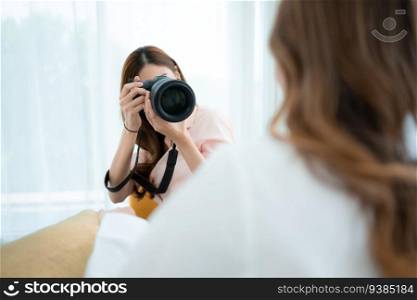 Beautiful asian woman photographer taking picture with professional camera at home