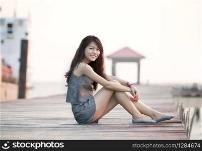 beautiful asian woman sitting on wood pier with relaxing emotion and smiling to camera use for attractive woaman and people female topic