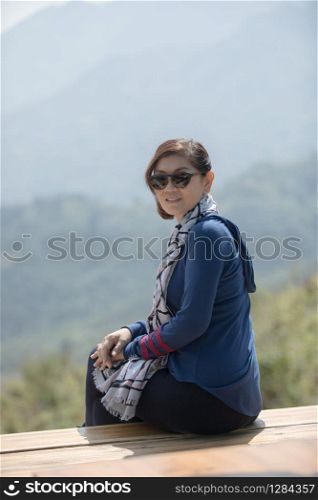 beautiful asian woman sitting on wood terrace with toothy smiling face